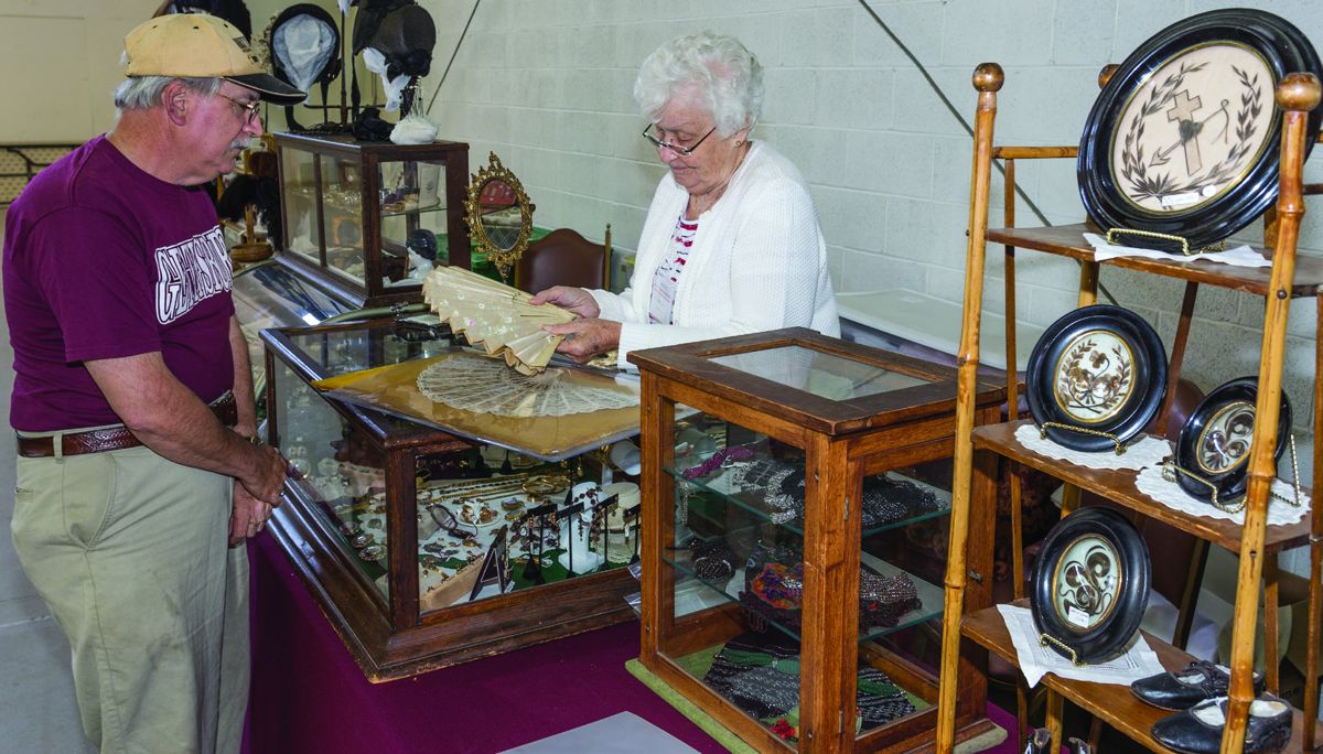 Not to be outdone by the military tables, Betty Loba of James River Emporium of McKnightstown, Pennsylvania, closely evaluates a lady’s fan as Dave Bommieno of New Jersey awaits her opinion.