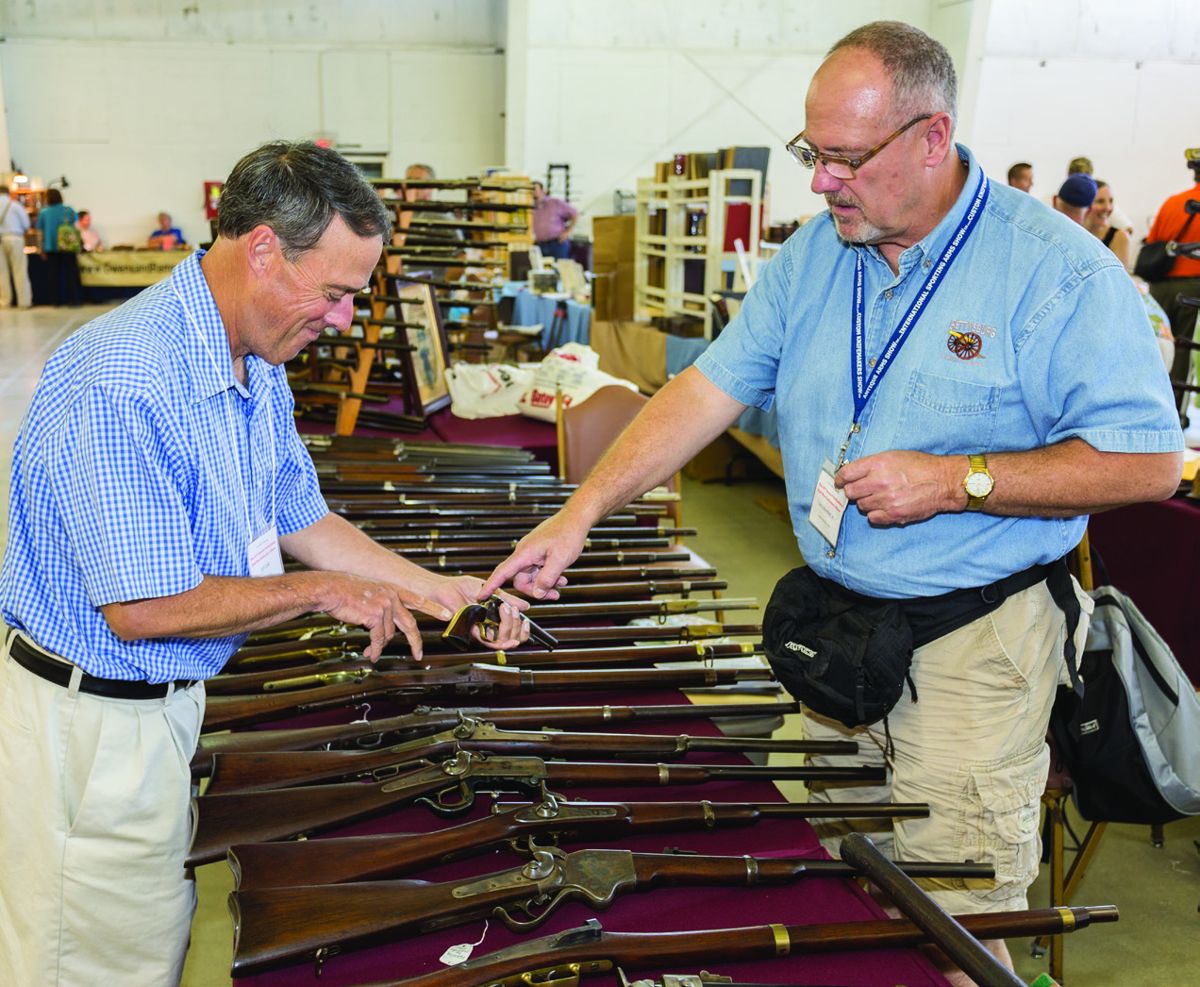 Larry Munther of Morristown, New Jersey, right, shows off a presentation pistol to fellow dealer Jeffrey Cook of Connecticut, left.