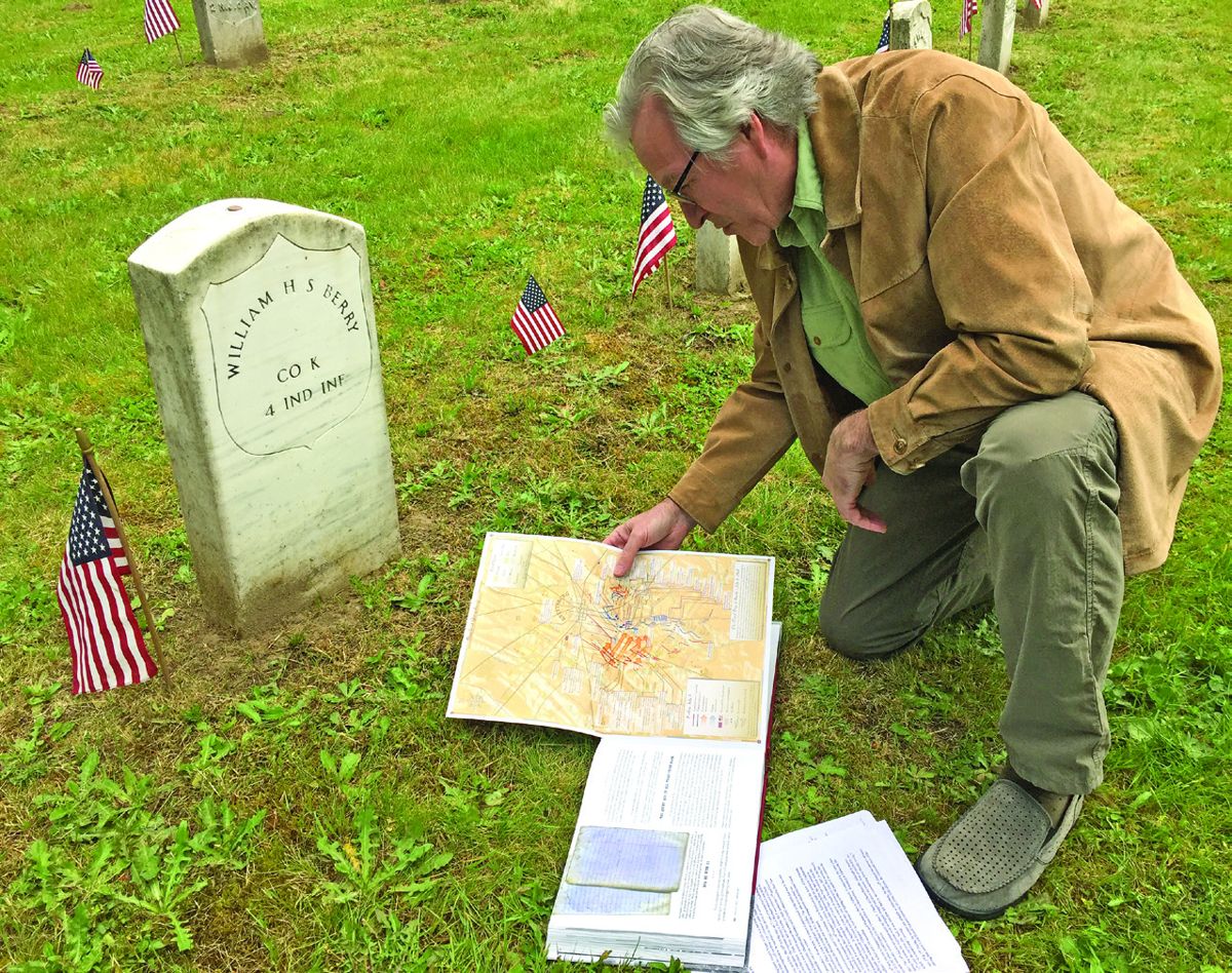 Author Thomas Pero, with his book Gettysburg 1863—Seething Hell opened at the grave site of William H.S. Berry.