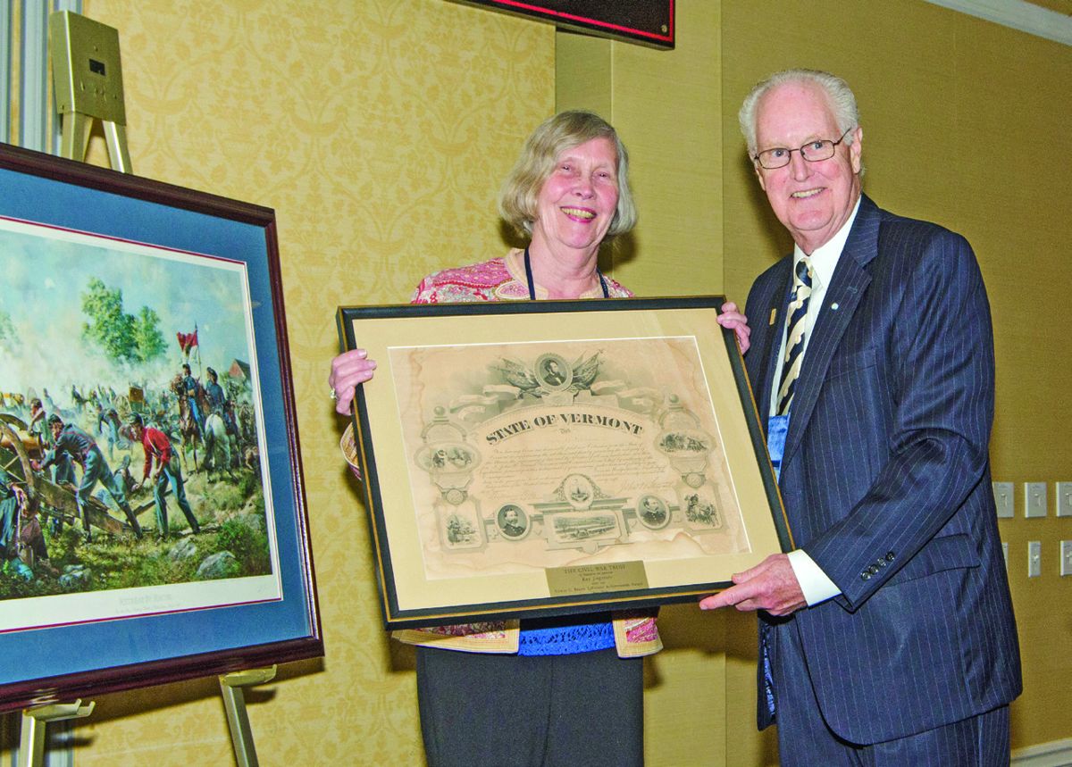 Civil War Trust President James Lighthizer presents retired Civil War News editor and publisher Kay Jorgensen with the Edwin C. Bearss Lifetime Achievement Award. She received a framed Vermont honorary enlistment certificate with plaque. Jorgensen donated the framed Don Troiani Gettysburg print “Retreat by Recoil,” at left, for which raffle tickets were sold.