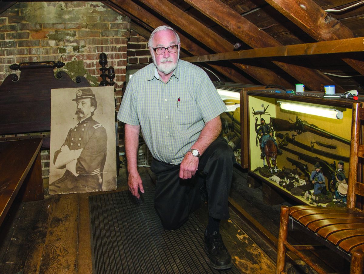 Loring Shultz, the proprietor of the Farnsworth House Inn, kneels next to a portrait of Union Major General Dan E. Sickles and next to his glass enclosed display of Civil War period artifacts. Minie balls have been discovered in the mortar in the attic.