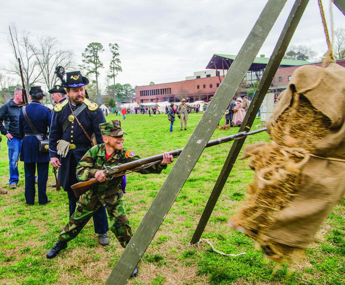 Young Marines member PFC Dominick Brown, 11 years old, tries his hand at striking the canvas covered hay bale with fixed bayonet. Standing behind him is Private Brian Withrow who has portrayed Lt.