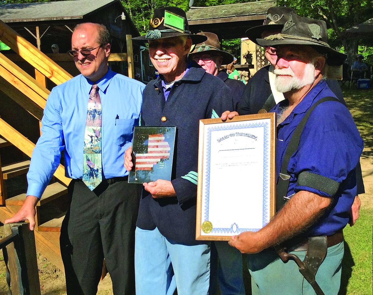 NWT Regional Commander Chuck Kindle (right) displays the Legislative Tribute and Huron Rangers Commander Henry Heatley (center) holds a photo of the adopted battle flag of the 5th Michigan Infantry. Both were presented by State Director of the Save the Flags project, Matt Van Acker (left), during the flag adoption ceremony at the skirmish at Laingsburg, Mich., on July 30, 2017.
