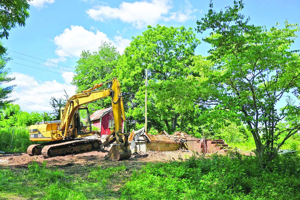 Workers demolish a condemned house on the property. (CVBT)