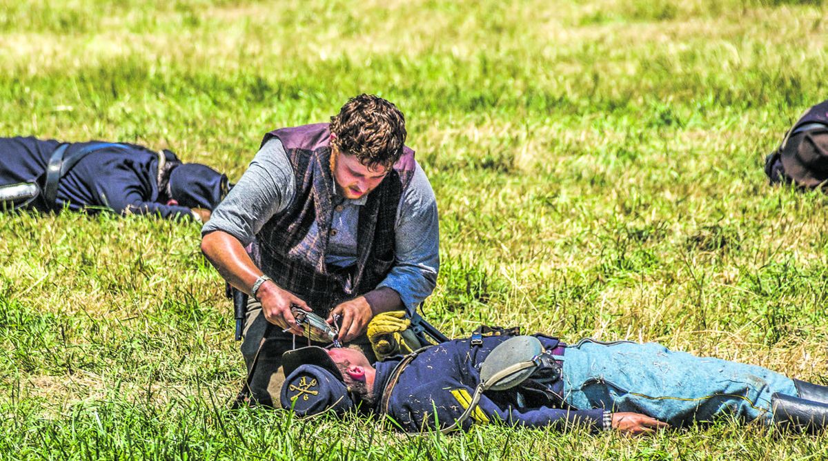 After trying valiantly to kill each other, soldiers from each side would perform small acts of mercy upon their earlier enemies. Here a Confederate pours life-giving water from his own canteen to slake the thirst of his Union opponent. (Sandy Goss, Eagle Bay Media)