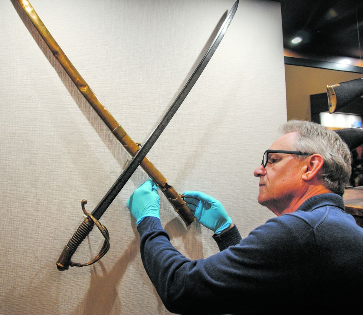 Exhibition technician Michael King installs the sword used by Confederate Brigadier General Arthur M. Manigault during the Battle of Atlanta. The brass scabbard still bears the mark of a bullet that nearly took the general’s life at Chickamauga.