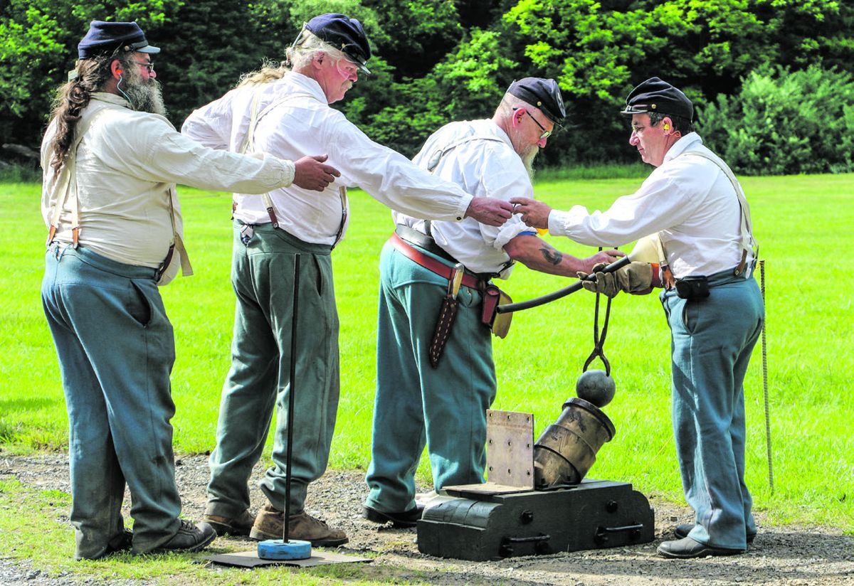 The 3rd U.S. Infantry mortar team members pass implements to each other while the loading of their 24-pounder Coehorn mortar.