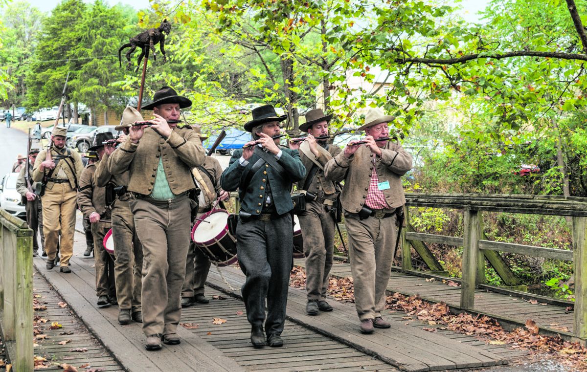 Music of the fifes and drums rally competitors in the second phase of the rifle musket match as they march across Back Creek to the range.