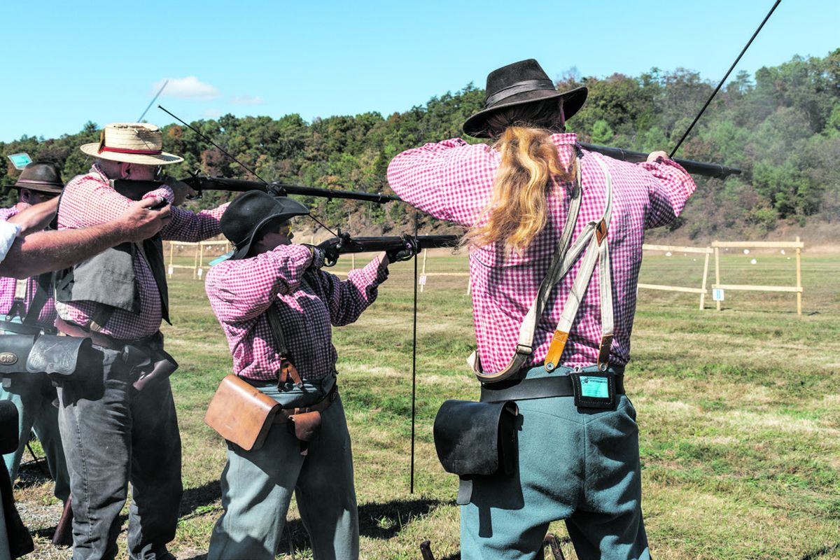 Music of the fifes and drums rally competitors in the second phase of the rifle musket match as they march across Back Creek to the range.
