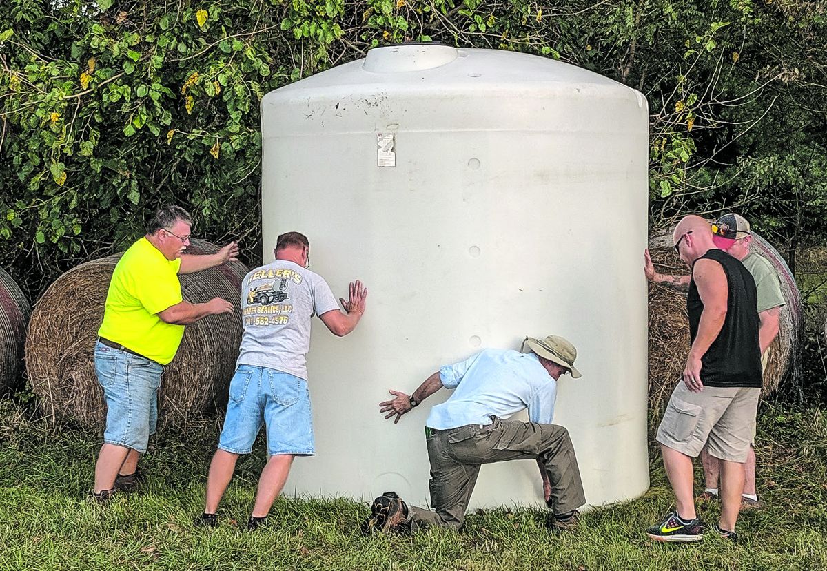 Shen ‘64. Volunteer Doug Dobbs (wearing hat) and local water company workers set up a water tank.