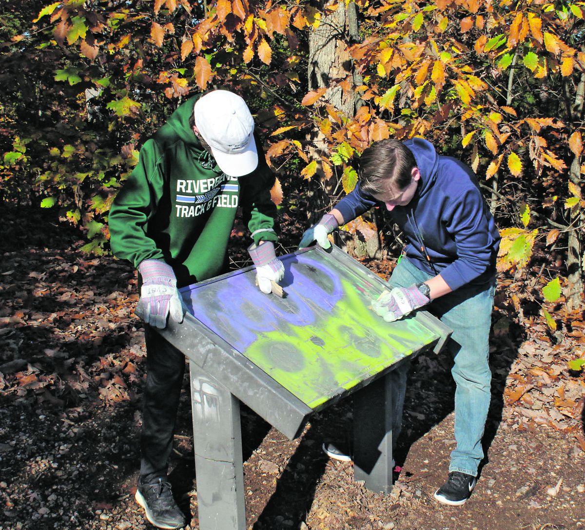 Nathan Alexander Lee and Noah Howell, students at Riverbend High School, scrub graffiti from an interpretive sign at Anderson Ridge on the Chancellorsville battlefield. They were among more than a dozen students and faculty from Riverbend to participate in Youth Community Service Day sponsored by Central Virginia Battlefields Trust.