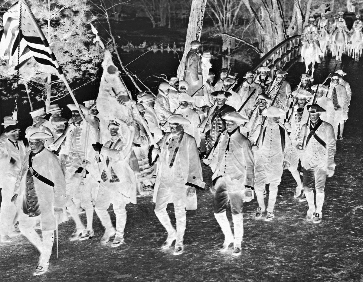 “Militiamen” march across Concord Bridge in 1925. Note “Indians” in canoes in left background.