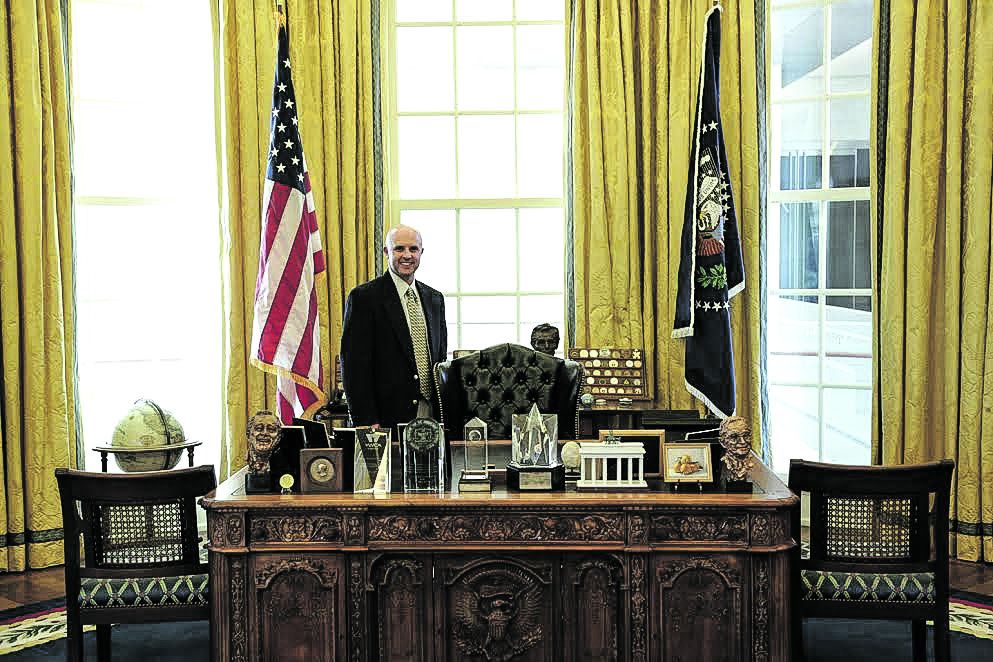 Todd Arrington stands behind a reproduction Oval Office desk.