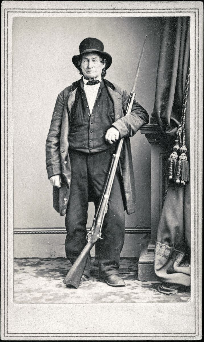 Carte de visite’s front and back views of John L. Burns, veteran of the War of 1812, a civilian who fought in the Battle of Gettysburg with Union troops, standing with bayoneted rifle musket. From photographic negative in Brady’s National Portrait Gallery. Creator: Brady’s National Photographic Portrait Galleries, photographer, New York: E. & H.T. Anthony, 501 Broadway. Medium: albumen print on card mount; mount 11 x 7 cm (carte de visite format).