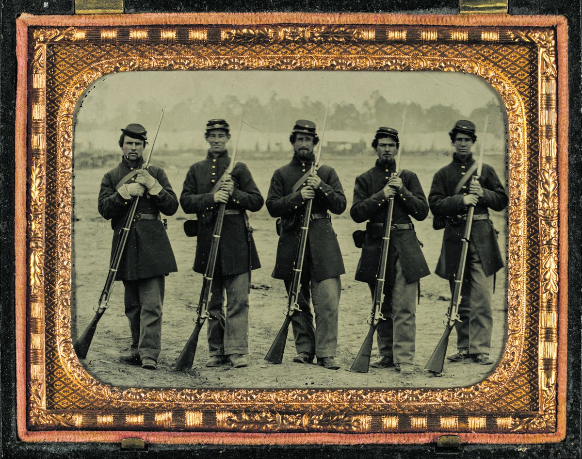 Five soldiers in Union uniforms of the 6th Regiment Massachusetts Volunteer Militia outfitted with Enfield rifle muskets and English accoutrements. Note the “expense pouch” apparently being utilized as a cap box worn on the front of the belt.