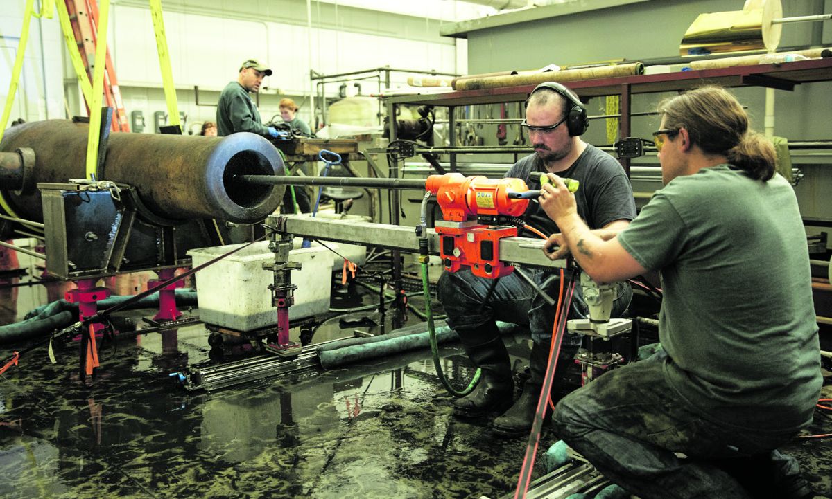 Director of Conservation Will Hoffman (far right) and Archaeological Conservator Erik Farrell focus intently on the boring process. Courtesy of Brock Switzer/The Mariners’ Museum and Park.