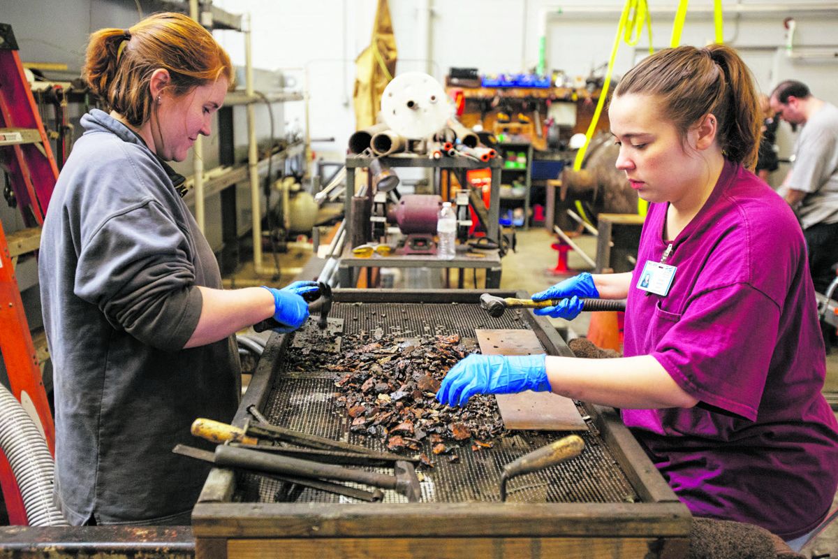 Material Culture Specialist Hannah Fleming (left) and Christina Altland examine materials removed from the gun for artifacts. Courtesy of Brock Switzer/The Mariners’ Museum and Park.