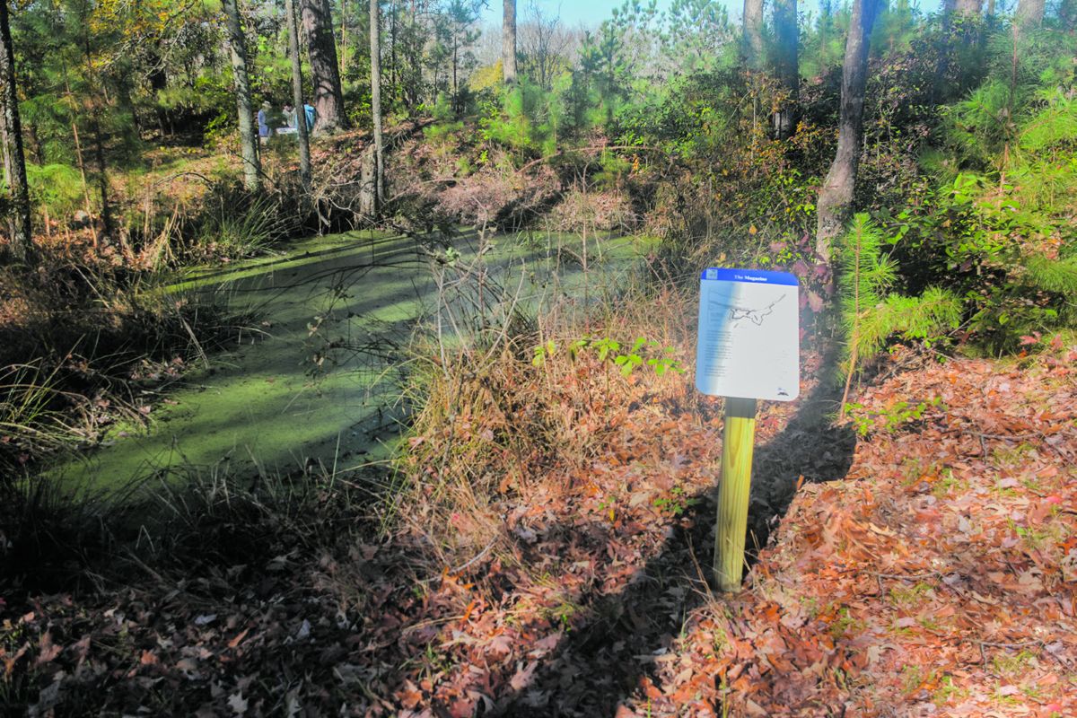 Magazine sign explains pond created when magazine was blown up in 1865. Gun emplacement sign crew in background.