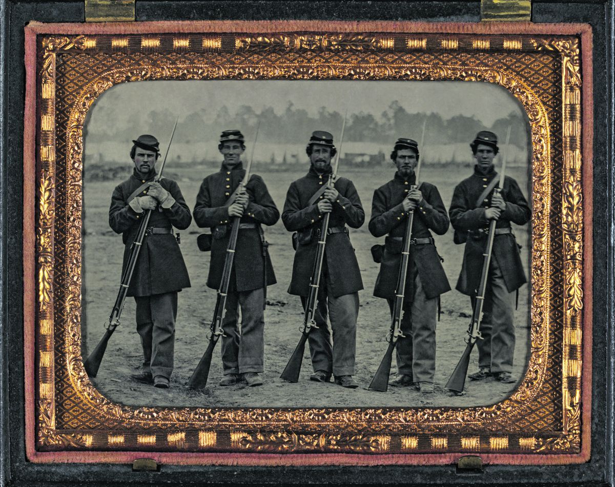 Five soldiers in Union uniforms of the 6th Regiment Massachusetts Volunteer Militia outfitted with P53 Enfield muskets, and Enfield leather accoutrements, in front of encampment. Liljenquist Family Collection of Civil War Photographs (Library of