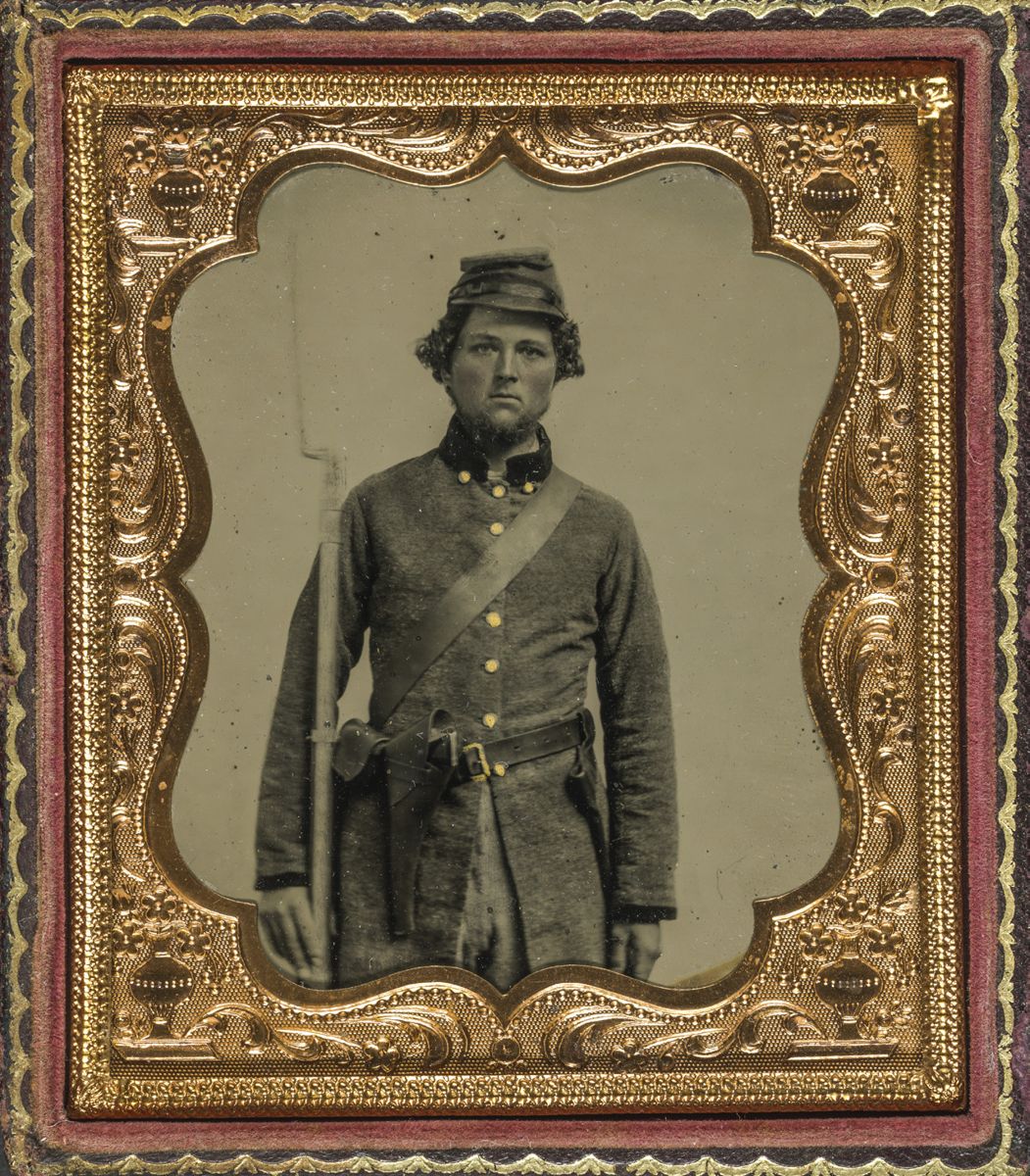 Confederate soldier wearing a frock coat, forage cap, accoutrement set with belt, percussion cap box, leather bayonet scabbard, bayoneted musket, and holstered revolver. Also is a sling for cartridge box hidden behind him. Liljenquist Family Collection of Civil War Photographs (Library of Congress).