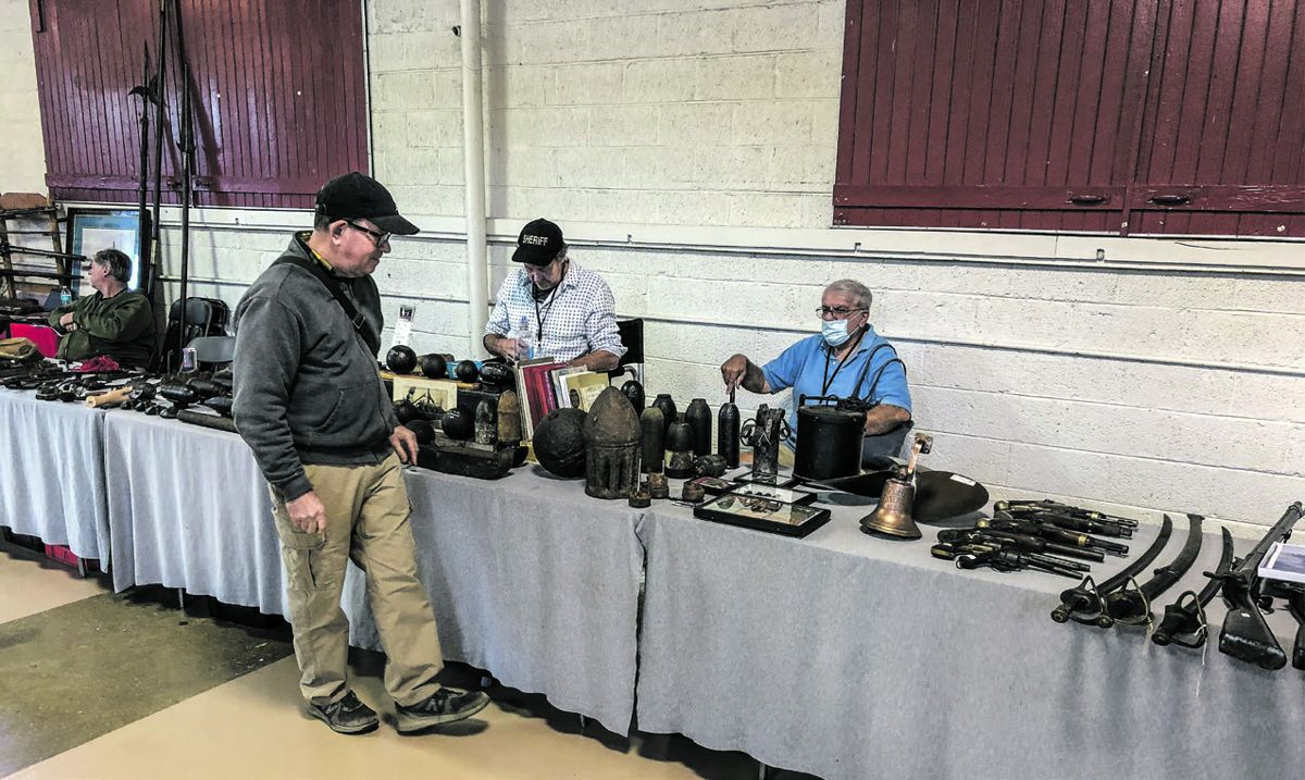 North Carolinian David Kornely (center) with artillery, guns, swords and interesting items for sale.