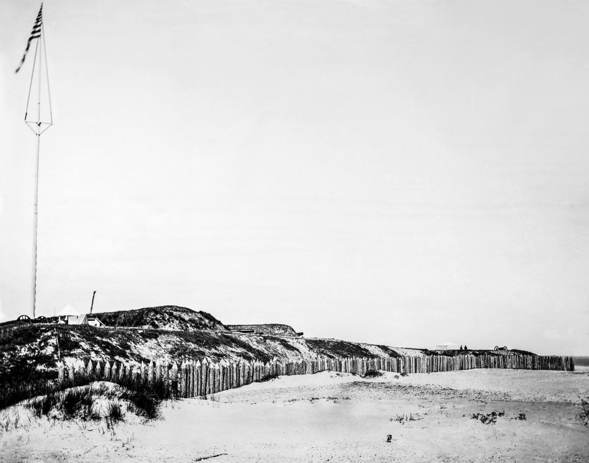 Fort Wagner sea face. This photo was taken from the red dot located on above drawing. The arrow shows the approximate direction of the camera. From left to right are 12-pounder, 32-pounder, 8-inch, another 32-pounder just left and below the far right tent, and a 12-pounder on the sea face.