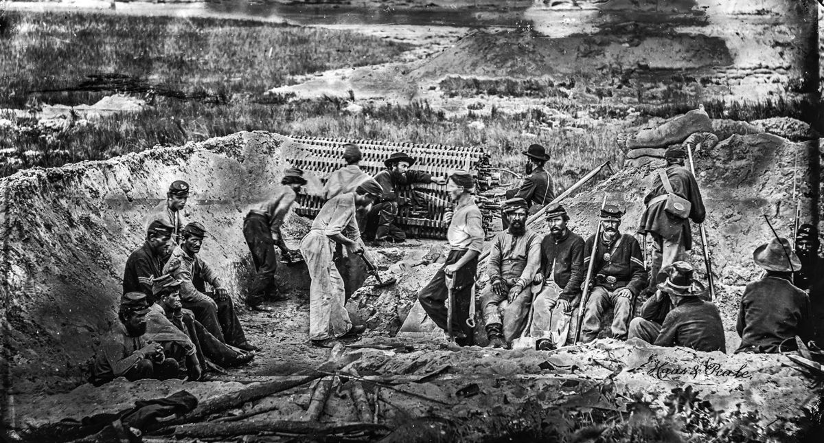 Union soldiers, some from Company C, 24th Regiment, Massachusetts Infantry, pose while digging a trench using a sap roller on Morris Island. (Library of Congress)
