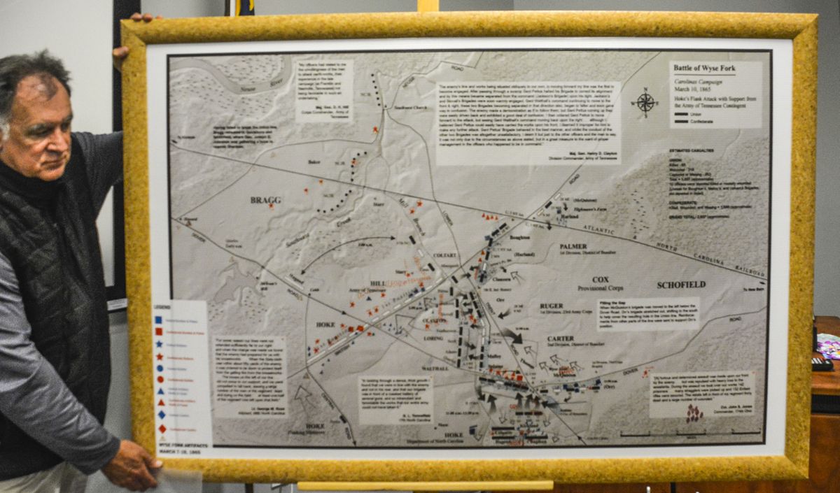 Dennis Harper orienting tour with map showing documented military positions and recovered artifacts.