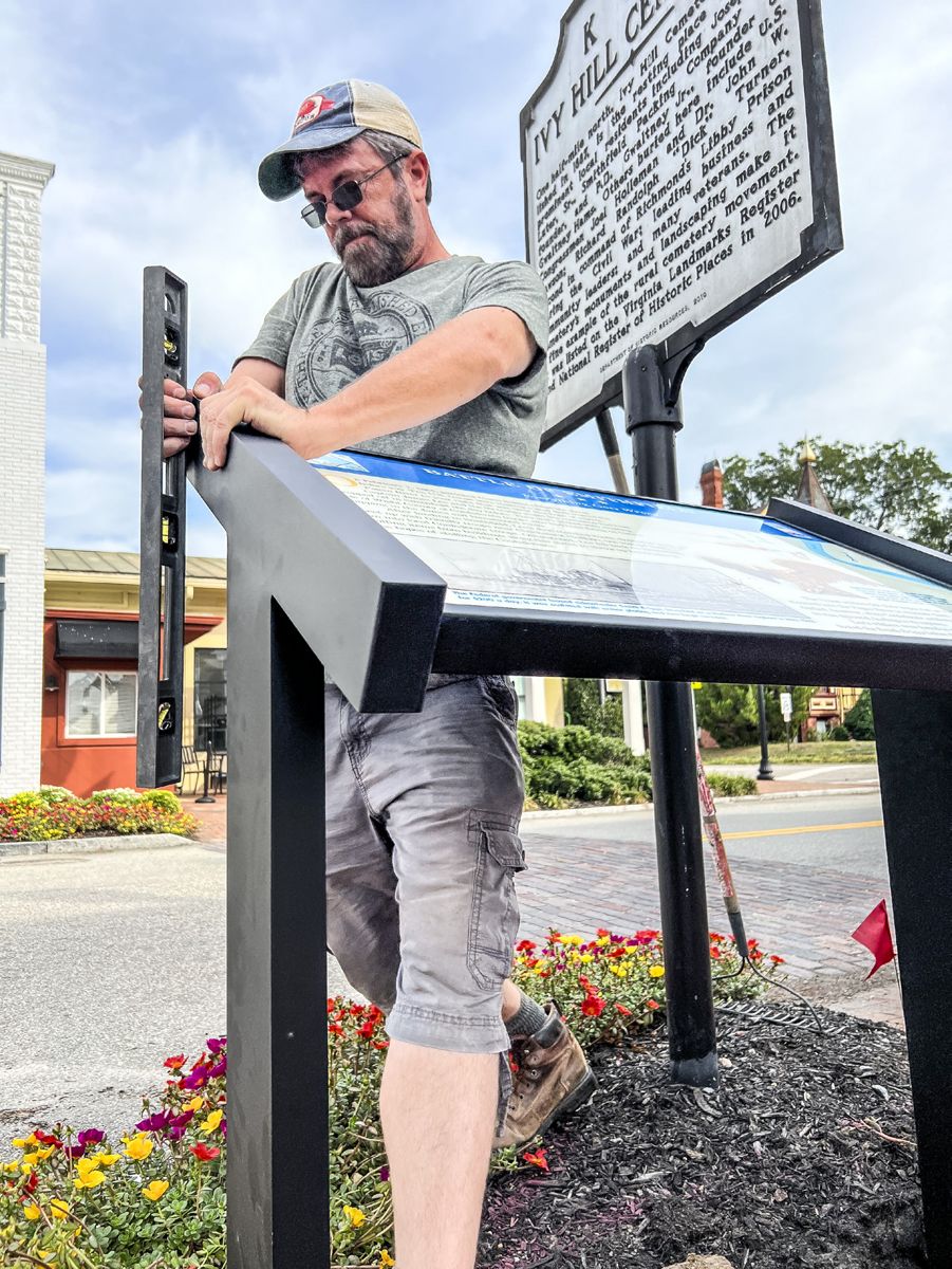 Jason Shaffer, Operations Manager for Civil War Trails, Inc., sets the new sign carefully next to the sidewalk located at 103 Main St., Smithfield, Va. (Photo courtesy of Civil War Trails Inc.)