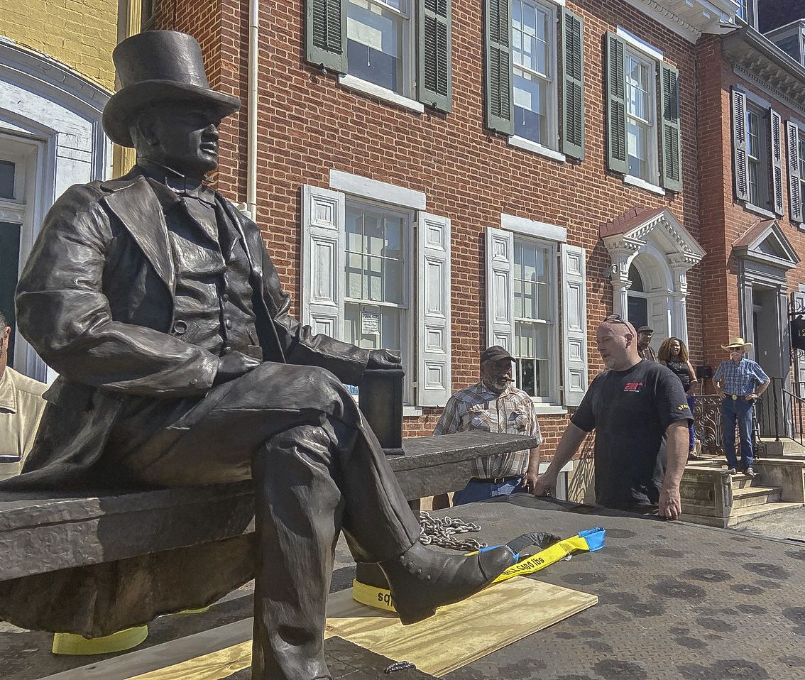 The statue sitting on truck bed in front of museum.